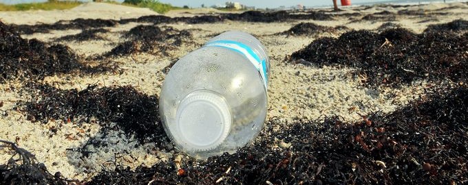 An empty plastic water bottle on the beach.